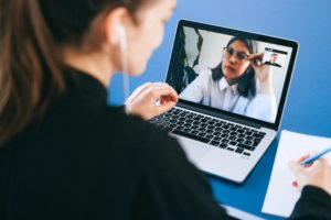 Coaching and mentoring have different outcomes. Woman talking via to a woman on a computer monitor.