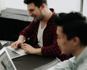 Two people at a desk working on laptop computers